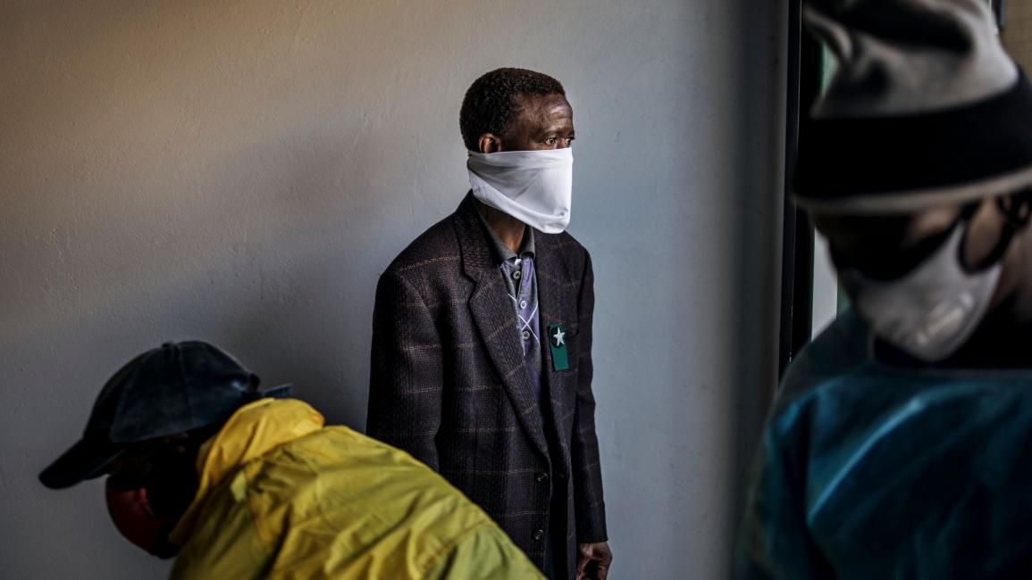 TOPSHOT-SAFRICA-HEALTH-VIRUS-FUNERAL TOPSHOT - A relative looks at the casket containing the remains of COVID-19 patient loaded in a hearse at the AVBOB mortuary in Soweto, on July 24, 2020. (Photo by MARCO LONGARI / AFP) (Photo by MARCO LONGARI/AFP via Getty Images)