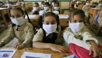 Egyptian school girls wear masks in class for protection against swine flu at a school in Cairo on October 4, 2009. Over 900 cases of the A(H1N1) flu have been reported in Egypt, and two people have died from it. Egypt, whose 80 million people make it the Arab world's most populous country, is already struggling with the deadly H5N1 strain of bird flu, and says it is not taking the swine flu lightly. AFP PHOTO/KHALED DESOUKI (Photo credit should read KHALED DESOUKI/AFP via Getty Images)