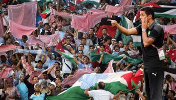 Amman, JORDAN: Jordanian fans wave their traditional chequered Kufiya (scarf) and their country's national flag as they cheer on their team Al-Faisali against Algerian opponents Entente Setif during the Arab Champions League final football match in Amman, 17 May 2007. Entente Setif was leading 1-0 at half-time. AFP PHOTO/MARWAN NAAMANI (Photo credit should read MARWAN NAAMANI/AFP via Getty Images)